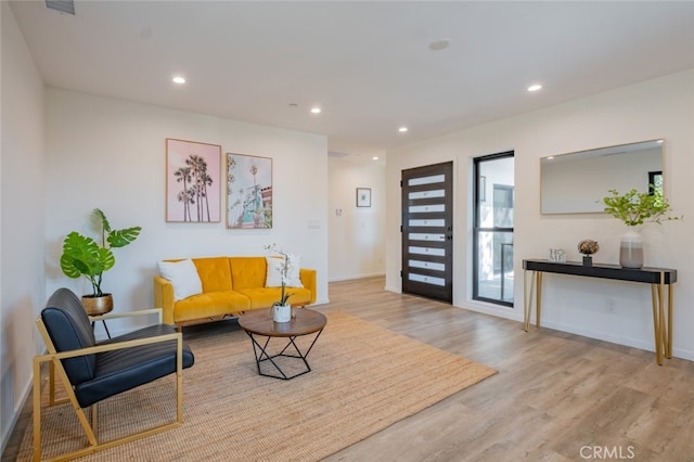 living area featuring baseboards, wood finished floors, and recessed lighting