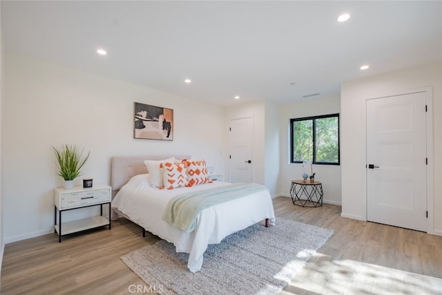 bedroom with light wood-type flooring, baseboards, and recessed lighting