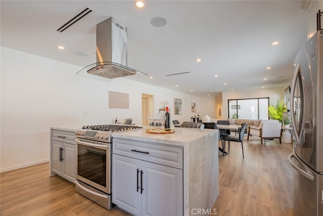 kitchen featuring light wood-style flooring, island range hood, visible vents, appliances with stainless steel finishes, and a center island