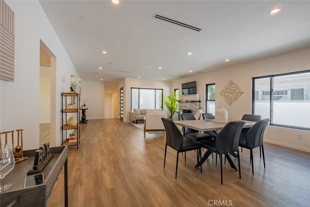 dining room featuring recessed lighting, visible vents, a fireplace, and wood finished floors