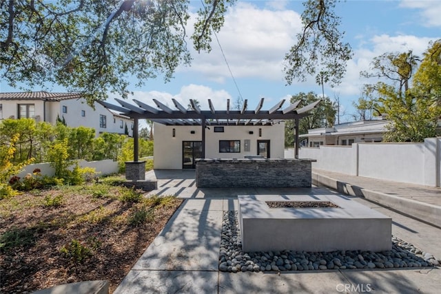 back of property with an outdoor fire pit, fence, stucco siding, a pergola, and a patio area