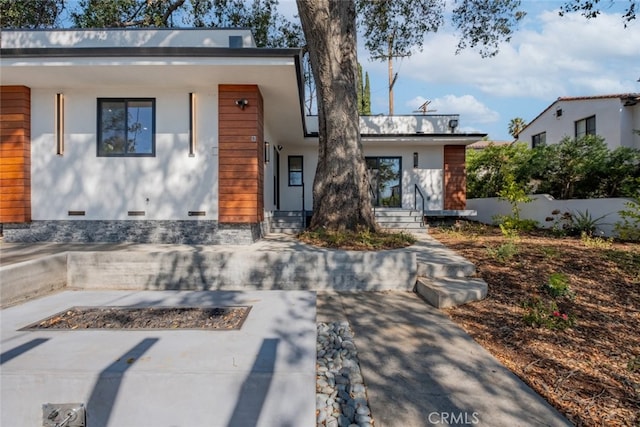 contemporary home featuring stucco siding, entry steps, crawl space, fence, and a fire pit