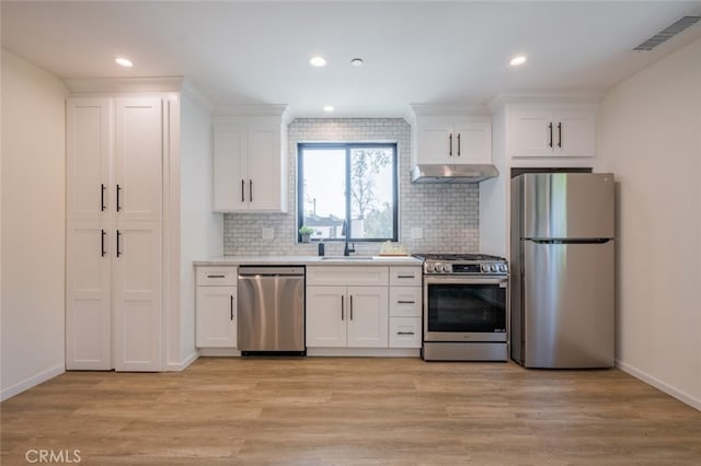 kitchen featuring visible vents, light wood-style flooring, appliances with stainless steel finishes, under cabinet range hood, and a sink