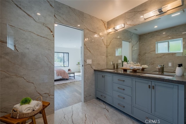 ensuite bathroom with stone wall, a sink, and tile walls