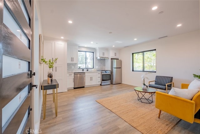 living area with light wood-type flooring, plenty of natural light, and recessed lighting