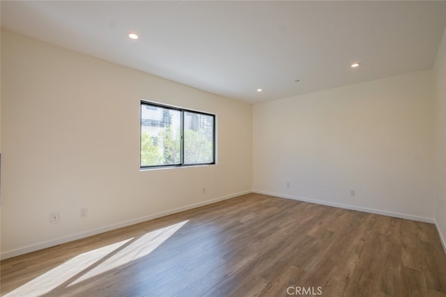 spare room featuring baseboards, wood finished floors, and recessed lighting
