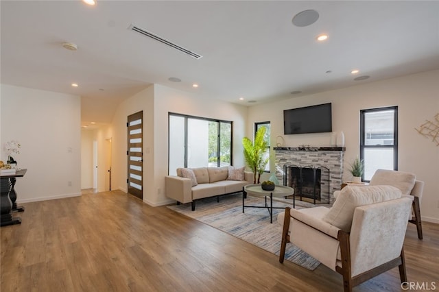 living room featuring baseboards, visible vents, wood finished floors, a fireplace, and recessed lighting