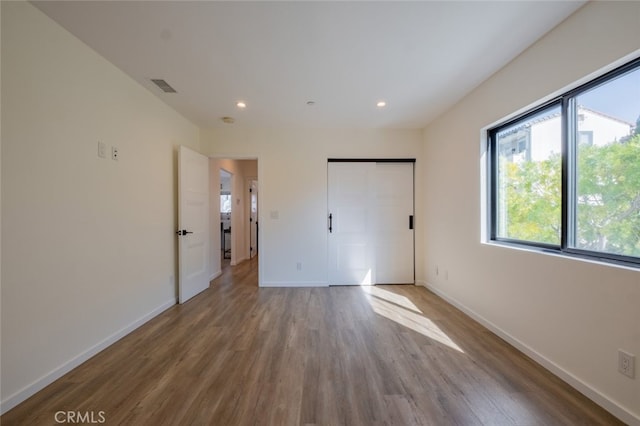 unfurnished bedroom with baseboards, visible vents, wood finished floors, and recessed lighting
