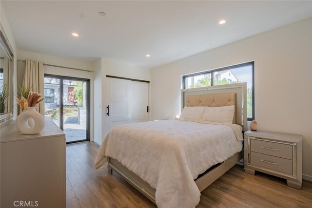bedroom featuring multiple windows, recessed lighting, wood finished floors, and access to exterior