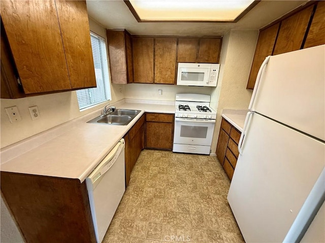 kitchen featuring light countertops, white appliances, brown cabinetry, and a sink