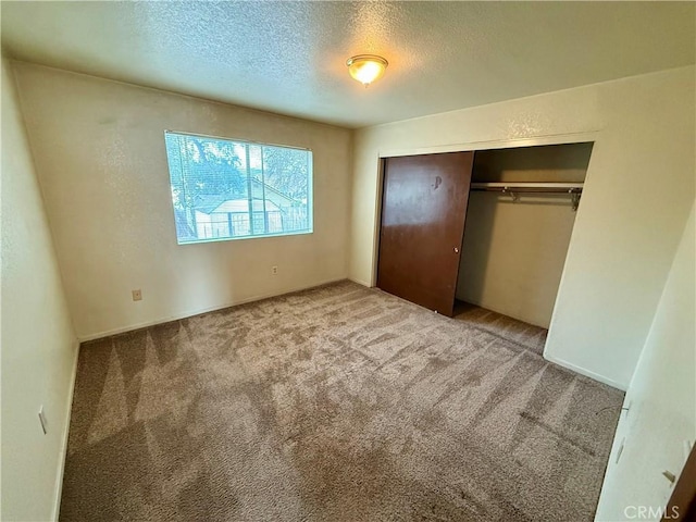 unfurnished bedroom with a closet, carpet flooring, a textured wall, and a textured ceiling