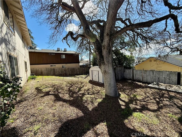 view of yard featuring a storage shed, a fenced backyard, and an outdoor structure