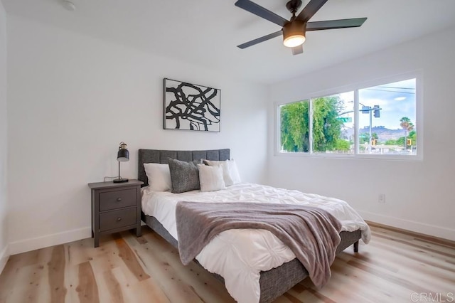 bedroom featuring light wood-style flooring, baseboards, and a ceiling fan