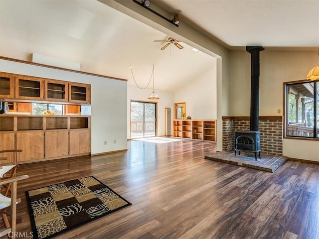 living area with dark wood-style floors, a wood stove, and a healthy amount of sunlight