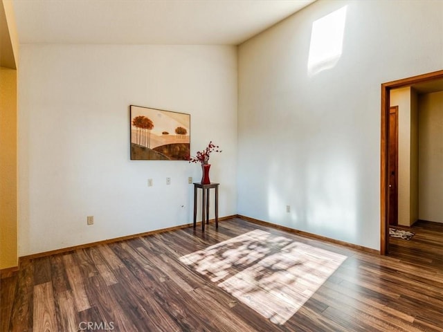 spare room with baseboards and wood finished floors