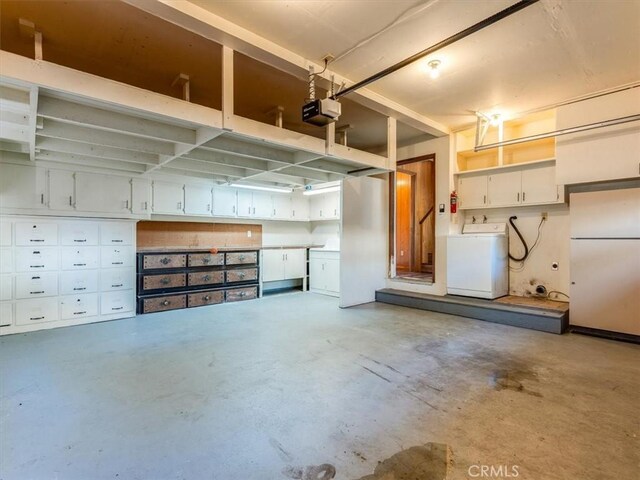 garage with a garage door opener, freestanding refrigerator, and washer / clothes dryer