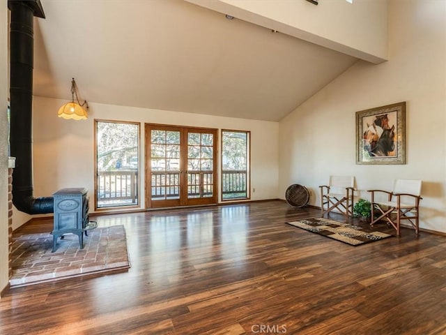 living area featuring high vaulted ceiling, a wood stove, french doors, and wood finished floors