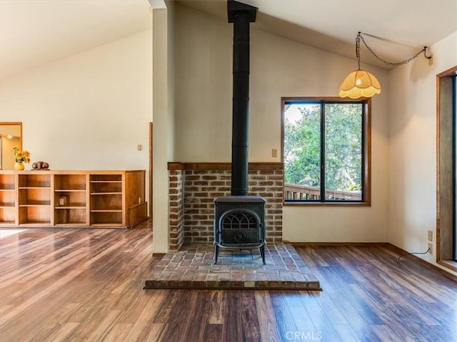 unfurnished living room featuring high vaulted ceiling, a wood stove, and wood finished floors