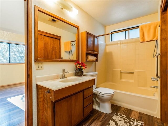 bathroom with toilet, shower / bathtub combination, wood finished floors, and vanity