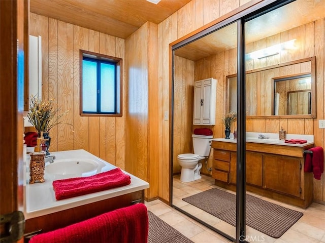 bathroom with toilet, vanity, and wooden walls