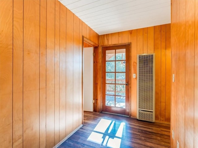 doorway to outside featuring wood walls, a heating unit, and wood finished floors