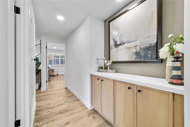 hall featuring baseboards, light wood-style flooring, and recessed lighting