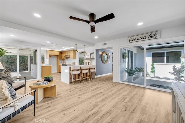 living area with baseboards, visible vents, a ceiling fan, light wood-style flooring, and recessed lighting