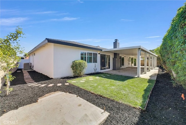 back of house with central air condition unit, fence, stucco siding, a chimney, and a patio area