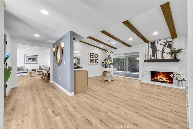 living area with lofted ceiling with beams, recessed lighting, a large fireplace, baseboards, and light wood-type flooring