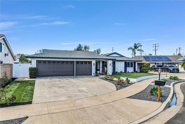 ranch-style home with a front lawn, a gate, fence, concrete driveway, and an attached garage