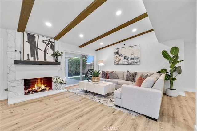 living room with lofted ceiling with beams, a warm lit fireplace, wood finished floors, and recessed lighting