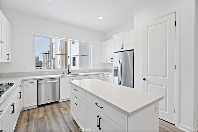 kitchen with a sink, white cabinetry, light wood-style floors, light countertops, and appliances with stainless steel finishes