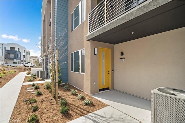 view of exterior entry featuring cooling unit and stucco siding