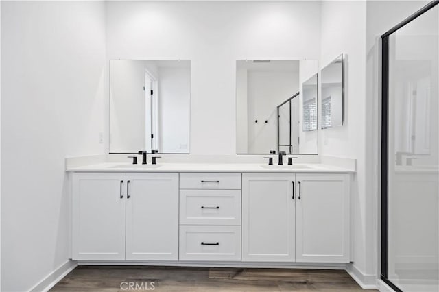 full bath with double vanity, wood finished floors, a sink, and baseboards