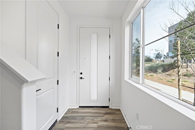 doorway featuring baseboards and wood finished floors