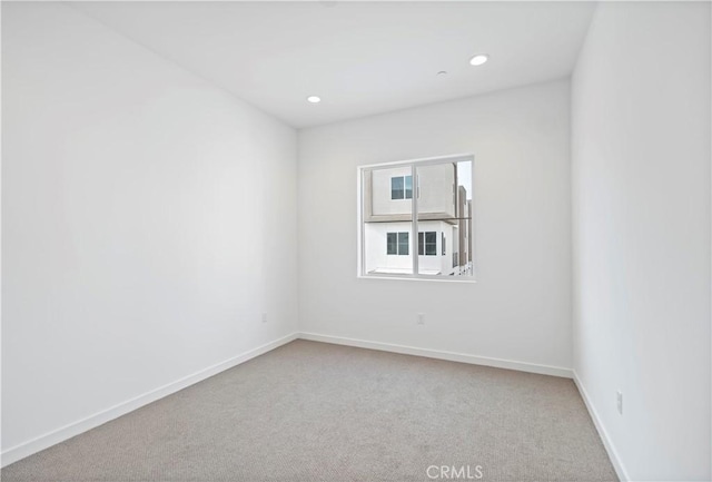 empty room with recessed lighting, light colored carpet, and baseboards