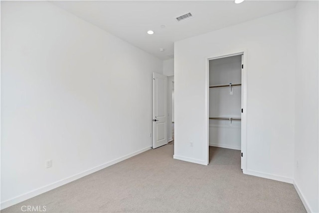 unfurnished bedroom featuring recessed lighting, visible vents, a spacious closet, light carpet, and baseboards