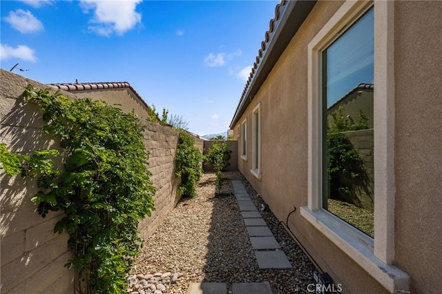 view of side of home featuring a fenced backyard and stucco siding