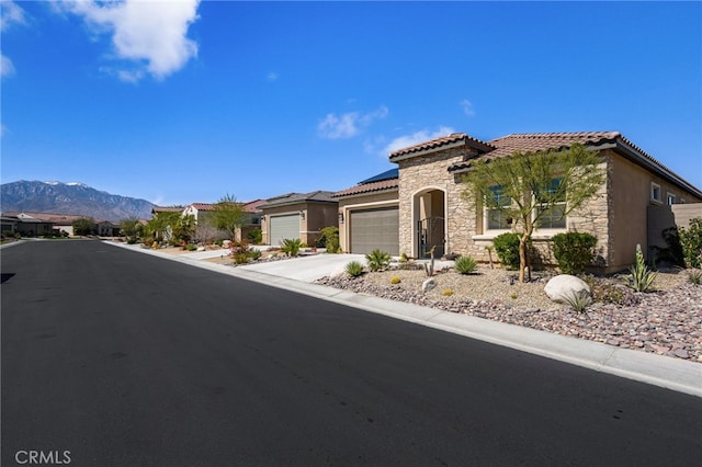 mediterranean / spanish home featuring a tile roof, stone siding, concrete driveway, a garage, and solar panels