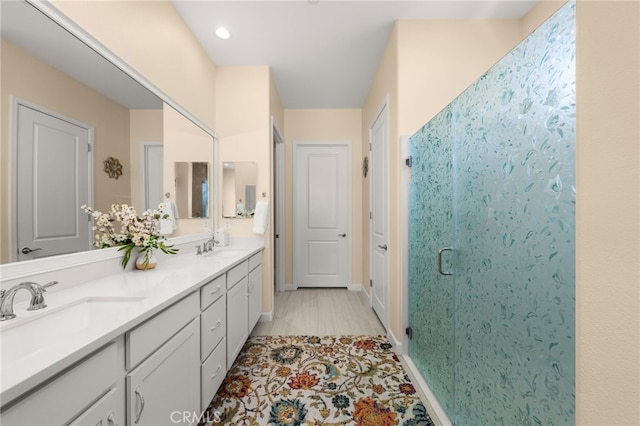 bathroom with a shower stall, double vanity, baseboards, and a sink