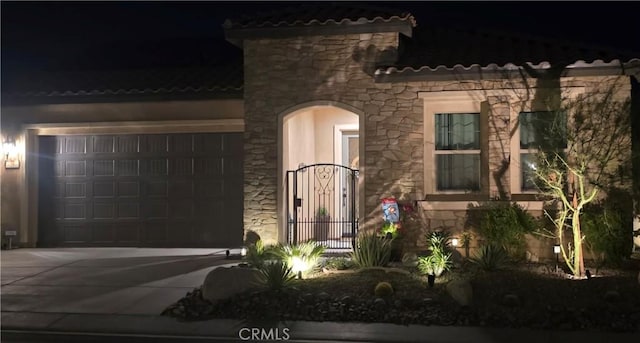 mediterranean / spanish house featuring stone siding, concrete driveway, and a tile roof