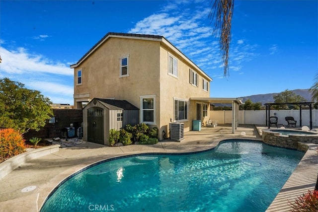 back of property with stucco siding, a fenced backyard, an outdoor structure, a patio area, and a storage unit