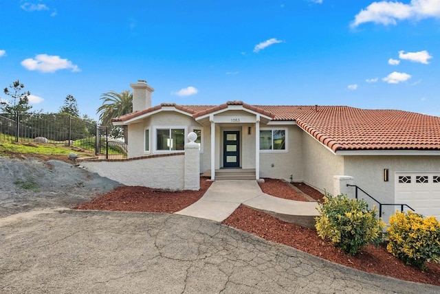 mediterranean / spanish home featuring a tiled roof, a chimney, fence, and stucco siding