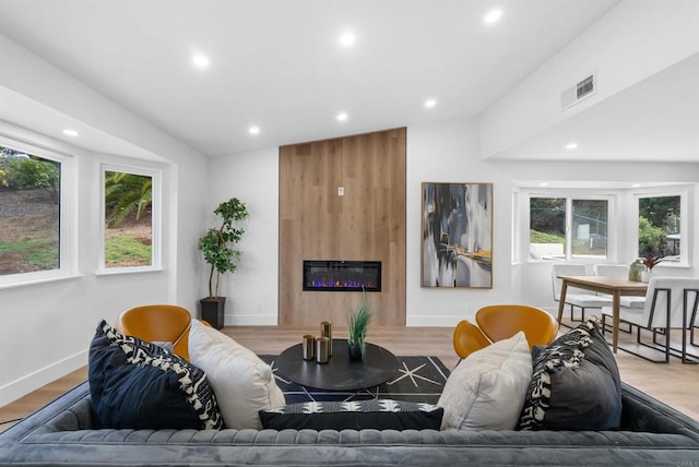 living room with a fireplace, visible vents, wood finished floors, and recessed lighting