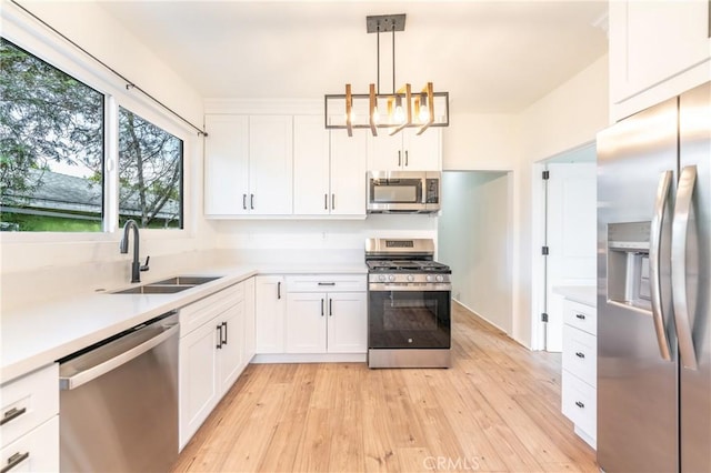 kitchen featuring white cabinets, light wood-style flooring, appliances with stainless steel finishes, light countertops, and a sink