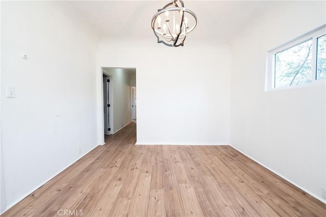 unfurnished dining area featuring an inviting chandelier, light wood-style flooring, and baseboards