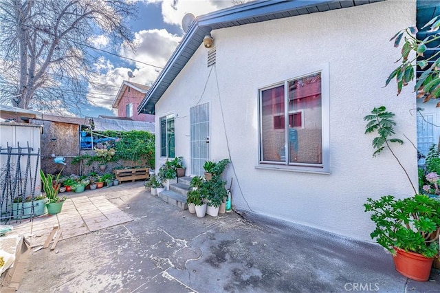 view of side of property with entry steps, a patio area, and stucco siding