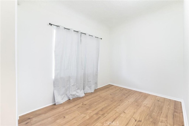 spare room with light wood-style flooring and baseboards