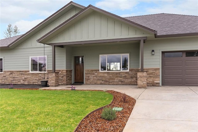 craftsman house with a shingled roof, stone siding, an attached garage, board and batten siding, and a front yard