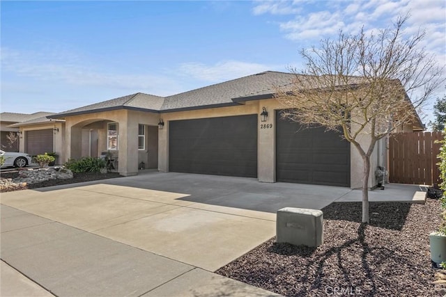 view of front of house featuring stucco siding, driveway, fence, roof with shingles, and an attached garage